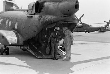 Lieutenant Colonel Thomas W. Holden, left, commanding officer of Marine Medium Helicopter Squadron 262 (HMM-262), prepares to undergo decontamination procedures with the aid of Corporal Marchezo during a combat readiness evaluation exercise. Corporal Marchezo is wearing nuclear-biological-chemical (NBC) gear. Lieutenant Colonel Holden is exiting a CH-46 Sea Knight helicopter