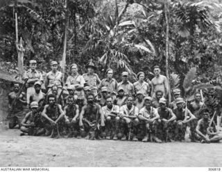 Bougainville, Solomon Islands. c. 1944-02. Group portrait of Coastwatchers and native police armed with rifles. Back row, left to right: Flight Lieutenant J. A. Corrigan, RAAF; Lieutenant (Lt) J. ..