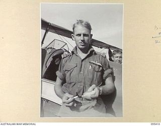 KIARIVU EMERGENCY LANDING GROUND, NEW GUINEA, 1945-08-13. FLYING OFFICER W.H.R. SMITH, 12 LOCAL AIR SUPPLY UNIT ROYAL AUSTRALIAN AIR FORCE BESIDE HIS AIRCRAFT. IT IS THE FIRST AIRCRAFT TO LAND ON ..