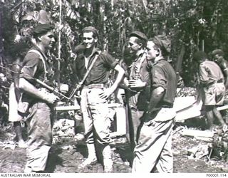 THE SOLOMON ISLANDS, 1945-04-24/27. FOUR AUSTRALIAN SERVICEMEN WITH A GROUP OF NATIVE PORTERS ON BOUGAINVILLE ISLAND. (RNZAF OFFICIAL PHOTOGRAPH.)