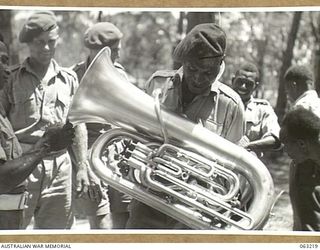 SOUTHPORT, QLD. 1944-01-18. A NEW GUINEA POLICE BOY ADMIRING THE EUPHONIUM OF TROOPER L. S. WATKINS, 4TH ARMOURED BRIGADE