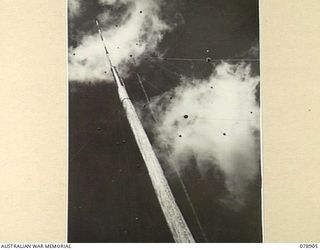 LAE AREA, NEW GUINEA. 1945-02-06. THE MAIN POLE AT THE WIRELESS TRANSMITTING CENTRE OF THE 19TH LINES OF COMMUNICATION SIGNALS, HEADQUARTERS, FIRST AUSTRALIAN ARMY. THIS WOODEN POLE IS 105 FEET ..