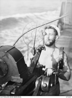 OFF MADANG, NEW GUINEA. 1944-05-14. ORDINARY SEAMAN A J BENSON (1), SIGHTS A 20MM OERLIKON ANTI AIRCRAFT GUN ABOARD THE RAN FRIGATE HMAS BARCOO