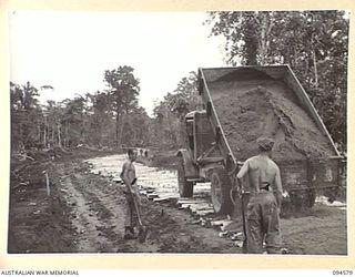 BOUGAINVILLE, 1945-07-31. A 3-TON TIP TRUCK OF 15 FIELD COMPANY, ROYAL AUSTRALIAN ENGINEERS, LAYING SAND OVER CORDUROY ON THE BUIN ROAD WEST OF THE OGORATA RIVER. IDENTIFIED PERSONNEL ARE:- SAPPER ..