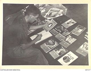 CAPE WOM, NEW GUINEA. 1945-09-29. SERGEANT J. MITCHELL, AUSTRALIAN ARMY EDUCATION SERVICE, HEADQUARTERS 6 DIVISION SELECTING EDUCATION MAGAZINES FOR DISTRIBUTION TO ALL UNITS IN THE DIVISION AS ..