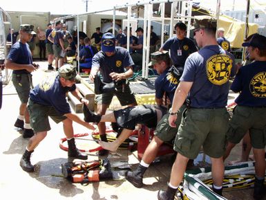 US Navy (USN) Divers from Mobile Diving and Salvage Unit One (MDSU-1) assist a fellow diver with his equipment after conducting training dives alongside the Crowley 450 Barge, in preparation for recovery operations for the Japanese fishing vessel Ehime Maru