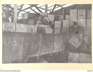 TOROKINA AREA, BOUGAINVILLE, SOLOMON ISLANDS. 1944-12-24. MEMBERS OF A WORKING PARTY LOAD A TRUCK WITH CHRISTMAS HAMPERS AT THE ISSUE POINT, 4 BASE SUB AREA FOR 4 FIELD REGIMENT TROOPS