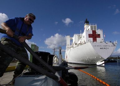 Mr. Nick Revuelto, a Line Handler at Naval Station Pearl Harbor, Hawaii (HI) helps to secure the mooring lines as the US Navy (USN) Military Sealift Command (MSC) Hospital Ship, USNS MERCY (T-AH 19), arrives in port at Naval Base Pearl Harbor, Hawaii (HI), for a brief port visit prior to deploying to Southeast Asia to provide assistance to victims of the devastating Tsunami that hit the region in support of Operation UNIFIED ASSISTANCE