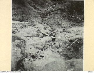 REINHOLD HIGHWAY, NEW GUINEA, 1944-02-25. WATER RUNNING DOWN THE FACE OF A SLOPE CAUSING THE UNDERMINING OF A ROAD AND A CONSEQUENT LANDSLIDE WHICH OCCURRED ABOUT 20 MILES FROM WAU