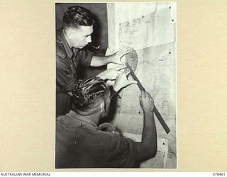 BOUGAINVILLE ISLAND, 1945-01-21. NX111086 MAJOR V.J.M. TRUDA (1) AND NX53522 GUNNER N.T. GROUNDS (2), PLOTTING TARGETS IN THE COUNTER BATTERY ROOM OF THE 2ND FIELD REGIMENT