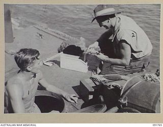 SORAKEN AREA, BOUGAINVILLE, 1945-05-06. SAPPER J. J. WHELAN, 26 INFANTRY BATTALION (A.I.F.) (1), COMES UP FROM A VERY HOT ENGINE ROOM FOR A BLOW WHILE ON DECK SAPPERJ.F. SMITH (2), LOADS THE ..