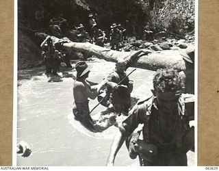 FARIA RIVER, RAMU VALLEY, NEW GUINEA. 1944-01-18. MEMBERS OF NO. 7 BATTERY, 2/4TH FIELD REGIMENT WADING THROUGH THE FAST FLOWING FARIA RIVER ON THEIR WAY TO FORWARD POSITIONS