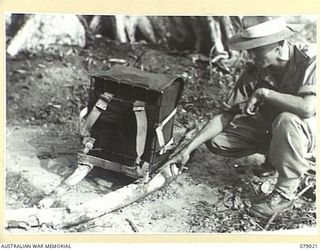 BOUGAINVILLE ISLAND. 1945-02-12. VX39063 CAPTAIN R.H.L. DUNN, 2/8TH FIELD AMBULANCE DEMONSTRATING A NEW TYPE OF AMBULANCE PACK WHICH IS BEING TESTED IN THE AREA