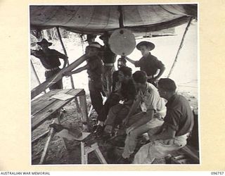 KARAWOP, NEW GUINEA, 1945-09-18. CPL H.N. CASTLES, EDUCATION SECTION, 2/6 CAVALRY COMMANDO REGIMENT, EXPLAINING TO PUPILS THE VARIOUS TYPES OF TIMBER