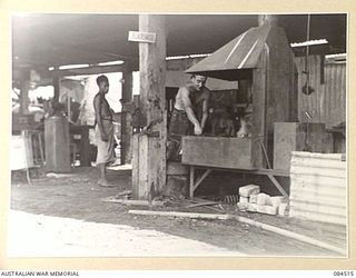 LABU, NEW GUINEA. 1944-12-18. CRAFTSMAN J. HORNER, BLACKSMITH, (1), AT 55 PORT CRAFT COMPANY WORKING OVER THE FORGE