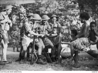 PAPUA, NEW GUINEA. 1942-07. ALTHOUGH THE OLDER FOLK ARE MORE WARY, THE YOUNG CHILDREN OF THE PAPUAN VILLAGES ARE QUICK TO MAKE FRIENDS WITH THE AUSTRALIANS. THE TROOPS SEEN IN THE PICTURE ARE ..