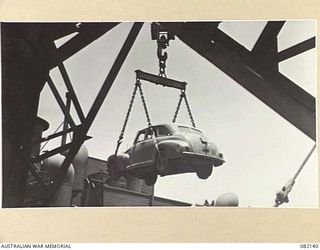 TOWNSVILLE, QLD. 1944-10-18. ELECTRIC CRANES LOADING STAFF CARS OF FIRST ARMY INTO HOLDS ABOARD THE LIBERTY SHIP SS JAMES OLIVER DURING EMBARKATION TO LAE, NEW GUINEA