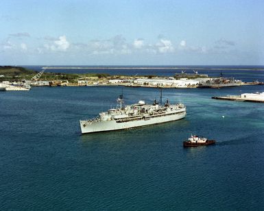 A harbor tug approaches the submarine tender USS PROTEUS (AS 19) in Apra Harbor