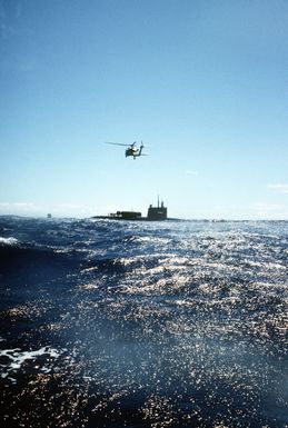 An HH-60H Seahawk helicopter hovers near the nuclear-powered submarine USS KAMEHAMEHA (SSN-642) off the coast of Oahu, Hawaii to drop off SEAL swimmers during a SSN/Helo air/sea rendezvous for special operations training