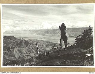 SHAGGY RIDGE, NEW GUINEA. 1944-01-22. LOOKING TOWARDS THE RAMU VALLEY FROM SHAGGY RIDGE SHOWING A MEMBER OF THE 2/9TH INFANTRY BATTALION BRINGING UP A SUPPLY OF AMMUNITION