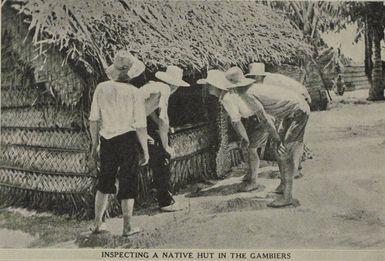 Men looking into a thatched hut while visiting Gambier Island