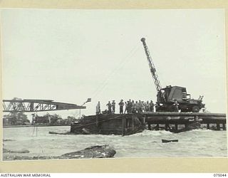 LAE, NEW GUINEA. 1944-08-09. TROOPS OF THE 20TH FIELD COMPANY, USING A LARGE MOBILE CRANE TO HAUL A STEEL BOX GIRDER SECTION OF THE NEW BRIDGE ACROSS THE BUTIBUM RIVER WHERE THE OLD WOODEN BRIDGE ..