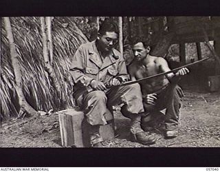 NADZAB, NEW GUINEA. 1943-09-19. MASTER SERGEANT USHIRO, JAPANESE AMERICAN INTERROGATOR OF THE UNITED STATES ARMY, ATTACHED TO HEADQUARTERS, 7TH AUSTRALIAN DIVISION, TRANSLATES JAPANESE MARKINGS ON ..