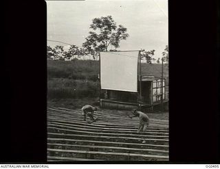 NEW GUINEA. 1944-01-08. SERGEANT H. H. SHIERS OF ADELAIDE, SA AND LEADING AIRCRAFTMAN B. DUGGAN OF KENSINGTON, NSW, REPAIRING SEATS AT AN OUTDOOR RAAF JUNGLE PICTURE THEATRE WHICH SEATS OVER ONE ..