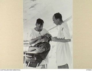 MILILAT, NEW GUINEA. 1944-08-23. NX77285 CAPTAIN J.H. PALMER, DENTAL OFFICER (1) ASSISTED BY NX166337 CORPORAL E.G. BLAKE, DENTAL ORDERLY (3) FILLING A TOOTH FOR NX118134 CORPORAL R. MCGAHEY, ..