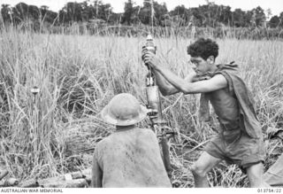 1942-12-08. NEW GUINEA. GONA. TREES IN THE BACKGROUND CONTAIN JAPANESE SNIPERS. AUSTRALIAN MORTOR CREWS IN ACTION 150 YARDS FROM GONA