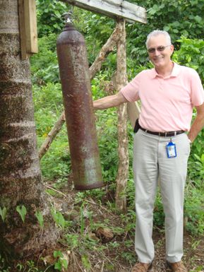 American Samoa, Dec. 9, 2010 -- Farley Howell, FEMA Region IX Federal Preparedness Coordinator, standing with the traditional warning bell in American Samoa. This method is being replaced by a DHS funded electronic warning system in the territory