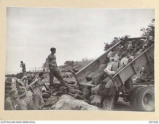 BOUGAINVILLE. 1945-05-02. A TIP TRUCK UNLOADING SAND BAGS FOR THE CONSTRUCTION, BY SAPPERS OF 2 FIELD COMPANY, ROYAL AUSTRALIAN ENGINEERS, OF A SEA WALL TO PREVENT ROAD WASH-AWAYS ALONG THE ..
