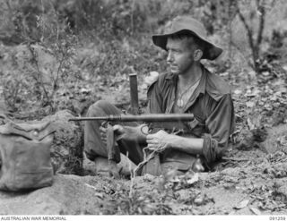AITAPE-WEWAK SECTOR, NEW GUINEA. 1945-04-26. PTE R.F. GAUDRY 2/3 INFANTRY BATTALION, WITH AN OWEN GUN IN A FORWARD PIT AT KALIMBOA VILLAGE