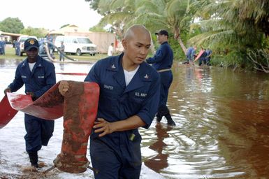 At Kauai, Hawaii (HI) PETTY Officers (PO) Alex Shafer (right) and Claude Ngouan assigned to the Ticonderoga Class Guided-missile Cruiser USS LAKE ERIE (CG 70) haul a discharge hose during a deflooding operation on the flood-stricken area