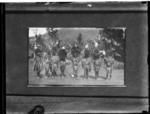 Seven men standing with feather head dress.