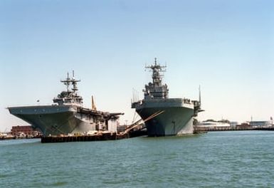 A bow view of the amphibious assault ships USS WASP (LHD-1), left, and USS SAIPAN (LHA-2) moored at pier No. 8