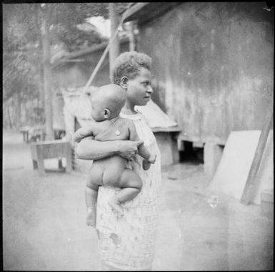 Woman holding a baby wearing a mission medal worn by the baby, New Guinea, ca. 1936, 2 / Sarah Chinnery