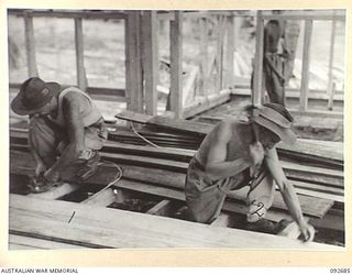TOROKINA, BOUGAINVILLE. 1945-05-31. SAPPER C.J. THOMPSON (1) AND SAPPER D.B. LAUGHTON (2), MEMBERS OF 10 FIELD COMPANY ROYAL AUSTRALIAN ENGINEERS, AT WORK ON THE FLOOR OF GLOUCESTER HOUSE. THIS ..