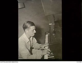 MADANG, NEW GUINEA. C. 1944-10. 424699 SERGEANT (SGT) PHILLIP HARGRAVE, ADELAIDE, SA, AN EMINENT AUSTRALIAN PIANIST IN CIVILIAN LIFE, BROADCASTING OVER RAAF RADIO, THE VOICE OF THE ISLANDS. THE ..