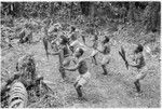 Dancers holding sango cordyline leaves outstretched in dance step