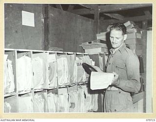 BOSLEY FIELD, BOUGAINVILLE, SOLOMON ISLANDS. 1945-03-15. VX111758 GUNNER J.E. RANN, PROGRAMME DIRECTOR, AUSTRALIAN ARMY BROADCASTING STATION, SELECTS RECORDINGS FOR THE EVENING PROGRAMME