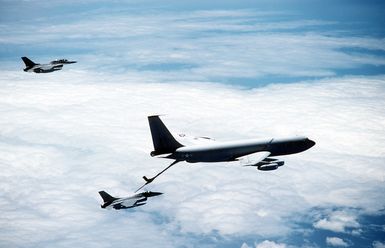 An air-to-air right side view of two F-16 Fighting Falcon aircraft undergoing refueling operations with a KC-135 Stratotanker aircraft, during a flight from March Air Force Base, Calif., to Hickam Air Force Base, Hawaii