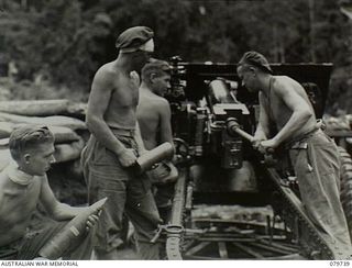 Pearl Ridge, Bougainville. 1945-03-09. Members of 4th Australian Field Regiment loading a 25 pounder gun with a smoke shell after propaganda leaflets have been inserted in cardboard containers in ..