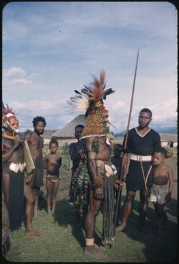 A man in full bilas (decoration), side view, being admired by station police : Wahgi Valley, Papua New Guinea, 1954-1955 / Terence and Margaret Spencer