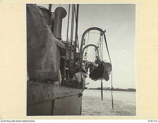 MADANG, NEW GUINEA. 1944-11-20. MEMBERS OF THE CREW OF THE ROYAL AUSTRALIAN NAVY VESSEL, HMAS "BENDIGO" HAULING A WHALEBOAT ABOARD WHILE THE VESSEL IS ANCHORED IN THE HARBOUR