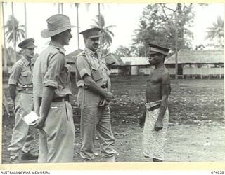 LAE, NEW GUINEA. 1944-07-22. MAJOR GENERAL B.M. MORRIS, DSO, GENERAL OFFICER COMMANDING, AUSTRALIAN NEW GUINEA ADMINISTRATIVE UNIT, ADDRESSING GARTER, A NATIVE "DOCTOR" WHO IS TO BE AWARDED A ..