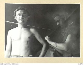 JACQUINOT BAY, NEW BRITAIN. 1944-11-10. QX48801 MAJOR P.S. WOODRUFF, DEPUTY ASSISTANT DIRECTOR OF HEALTH, 5TH DIVISION (2), GIVING A CHOLERA NEEDLE TO QX52591 DRIVER A. HANLEY (1) IN THE UNIT ..