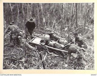 WEWAK AREA, NEW GUINEA, 1945-06-27. MEMBERS OF 2/8 INFANTRY BATTALION EVACUATING A STRETCHER CASE DURING THE UNIT'S ACTION AGAINST JAPANESE POSITIONS ON MOUNT SHIBURANGU