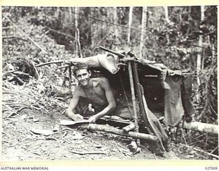 PAPUA, NEW GUINEA. 1942-09. A MEMBER OF THE 55TH AUSTRALIAN INFANTRY BATTALION, SHOWING A TYPICAL HOME IN WHICH TROOPS LIVE, IN THE OWEN STANLEY RANGES