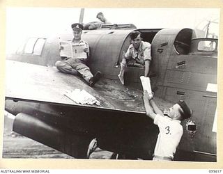 LAE AREA, NEW GUINEA. 1945-08-31. A SPECIAL RAAF BEAUFORT AIRCRAFT COURIER TAKING COPIES OF THE ARMY NEWSPAPER GUINEA GOLD FOR DELIVERY. IDENTIFIED PERSONNEL ARE:- FLIGHT SERGEANT J.B. MORRIS, ..